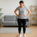 A young woman standing on a home weighing scale, checking her weight in a bright, minimalistic room.