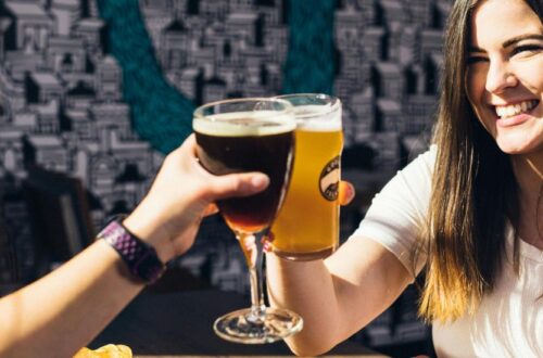 A couple sitting together and raising their glasses for a cheerful toast, symbolizing modern drinking culture in France and Italy.