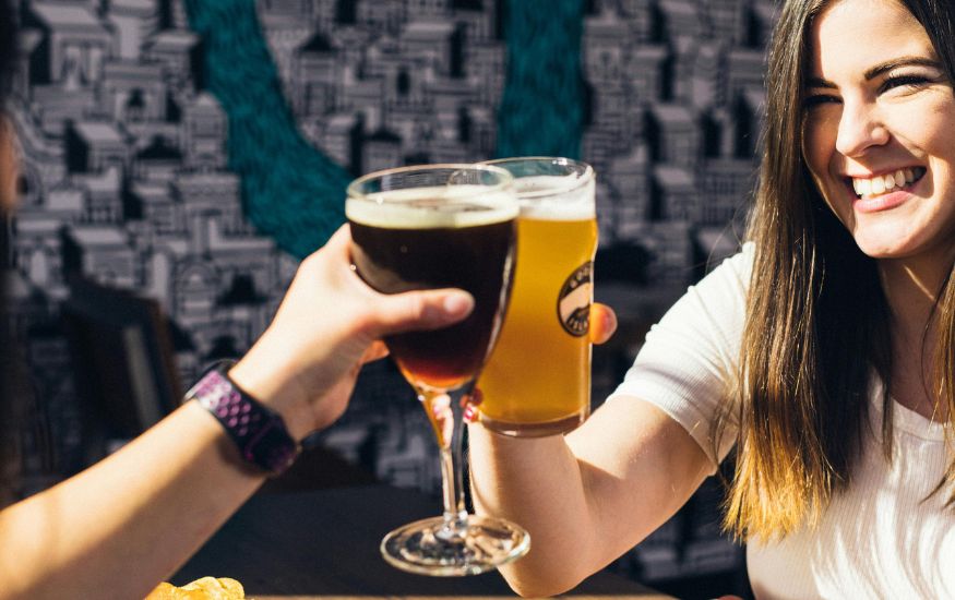 A couple sitting together and raising their glasses for a cheerful toast, symbolizing modern drinking culture in France and Italy.