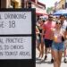 A black sign on a busy Mexican street explaining What Is the Legal Drinking Age in Mexico. The sign states that while the legal age is 18, actual practice varies and ID checks are rare in tourist areas.