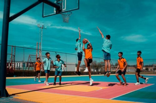 A dynamic group of young athletes playing an intense game on a colorful outdoor court, providing a visual example for the rule What Is Travel in Basketball.