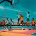 A dynamic group of young athletes playing an intense game on a colorful outdoor court, providing a visual example for the rule What Is Travel in Basketball.