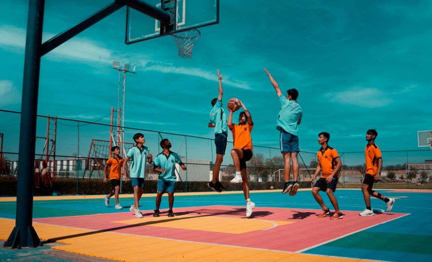 A dynamic group of young athletes playing an intense game on a colorful outdoor court, providing a visual example for the rule What Is Travel in Basketball.