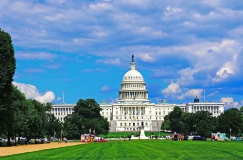 Things to Do in Washington, DC With Kids: The majestic United States Capitol building surrounded by lush green lawns and colorful food trucks under a bright blue sky with fluffy white clouds.