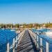 Things to Do in Rockland, Maine - Wooden pier extending into the blue water of Rockland Harbor with docked boats and coastal town buildings in the background.