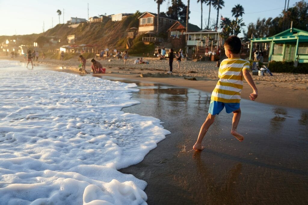 Young boy running along the shore, highlighting fun beach and water.