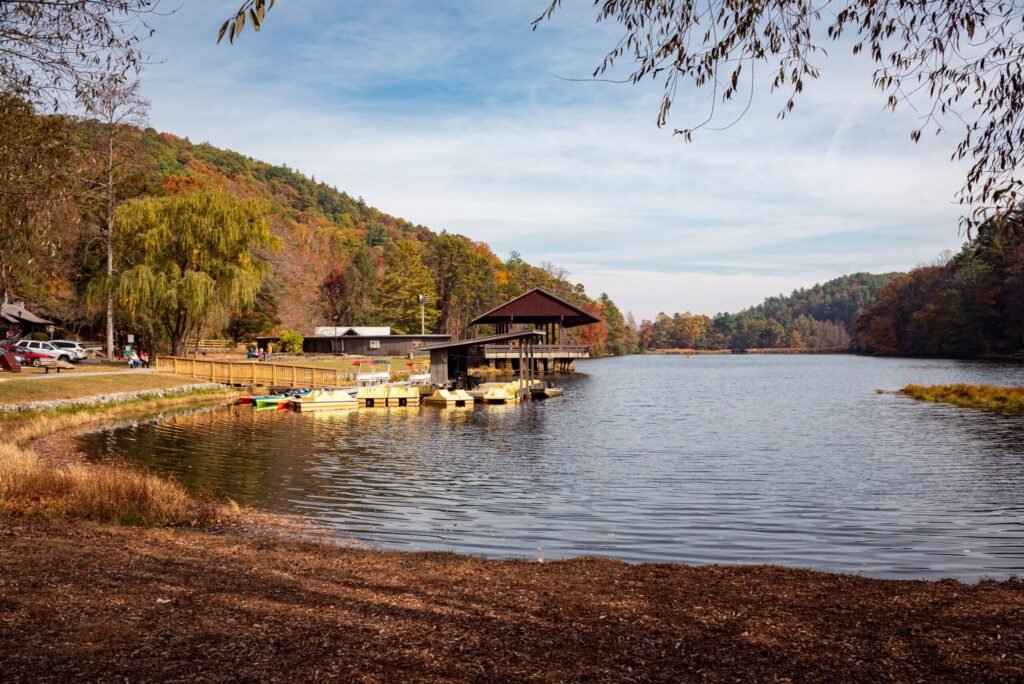 Scenic autumn lake in Georgia, USA, with colorful trees, boats, and a wooden dock, showcasing outdoor attractions near hot springs in Georgia.